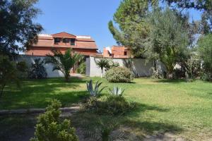 una casa con un patio con árboles y césped en Bedda Casa Al Mare en Agnone Bagni