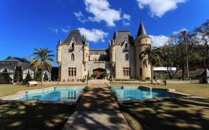 a large castle with a swimming pool in front of it at Vila da Sol Itaipava casas e estúdios in Itaipava
