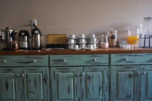 Hotel Sienna في ميندوزا: طاولة مطبخ مع خزانات خضراء وأكواب عليها