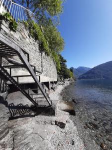 un mur en pierre et des escaliers à côté d'une masse d'eau dans l'établissement Villa del Pescatore, à San Siro