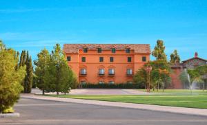 エルモシージョにあるHotel Boutique Villa Toscanaの目の前に木々が植えられた大きなオレンジ色の建物