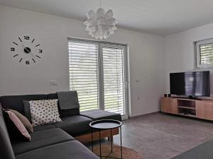 a living room with a couch and a clock on the wall at Brand new house Luna in Bled