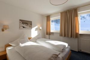 a bedroom with two beds and two windows at Chalet Schneekristall in Lech am Arlberg