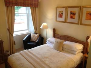 een slaapkamer met een bed, een stoel en een raam bij Buccleuch Guest House in Fort William