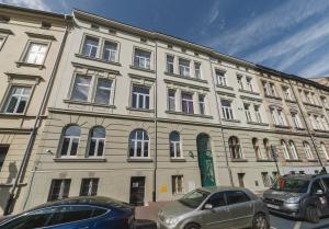 un grand bâtiment avec des voitures garées devant lui dans l'établissement Barbakan Residence Old Town, à Cracovie