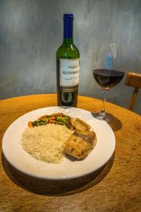 a plate of food with rice and a bottle of wine at Jardins Motel (Adults Only) in Maceió