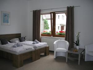 a bedroom with two beds and a chair and a window at Villa Vlasta in Karlovy Vary