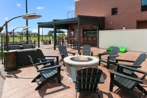 a patio with chairs and a fire pit in front of a building at Cobblestone Hotel & Suites Appleton International Airport in Neenah