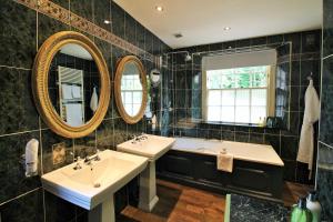 a bathroom with two sinks and two mirrors at The Swan Hotel in Bibury