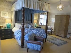 a bedroom with a canopy bed and a chair at The Swan Hotel in Bibury