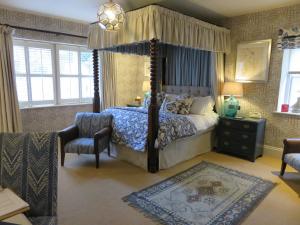 a bedroom with a canopy bed and a chair at The Swan Hotel in Bibury