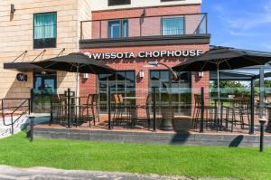 a restaurant with chairs and umbrellas in front of a building at Cobblestone Hotel & Suites Appleton International Airport in Neenah