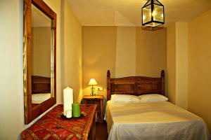 1 dormitorio con cama, espejo y mesa en CASA RURAL LA CABRERA, en Casas del Castañar