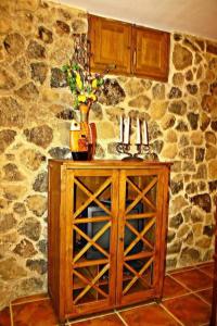 un armario de madera con un jarrón en la parte superior de una pared de piedra en CASA RURAL LA CABRERA, en Casas del Castañar