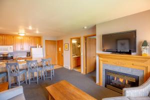 a living room with a fireplace with a television and a kitchen at Westwood Shores Waterfront Resort in Sturgeon Bay