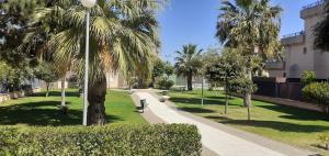 un parque con bancos y palmeras y un edificio en Apartamento acogedor en lugar inmejorable, en Sanlúcar de Barrameda
