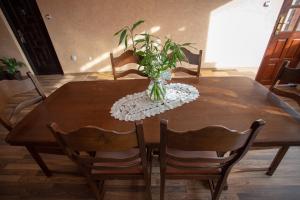 a dining room table with a vase with a plant on it at Vila Tei GuestHouse in Târgu Jiu