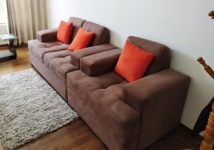un sofá marrón con almohadas naranjas en la sala de estar. en Real House Cusco, en Cusco