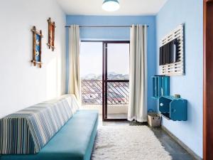 カラグアタトゥーバにあるApartamento em Caraguatatubaのベッドルーム1室(窓の前に青いソファ付)
