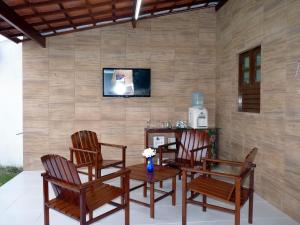 Habitación con 4 sillas y mesa con TV. en Casa OhVidaBoa com 6 suítes, en Natal