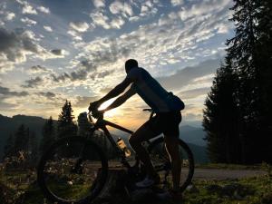 a man riding a bike on a hill with the sunset at Appartementhaus Sky Lodge in Altenmarkt im Pongau