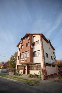 a brown and white building next to a street at Vila Tei GuestHouse in Târgu Jiu