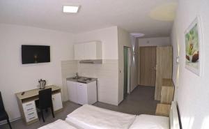 a room with a bed and a desk and a kitchen at Pension Kochertal in Aalen