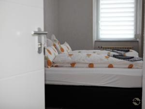 Bett mit weißer Bettwäsche und orangefarbenen und weißen Kissen in der Unterkunft Bianca`s Hotel Restaurant in Lörrach