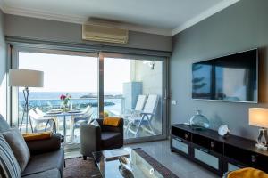 a living room with a couch and a tv and a balcony at Teresita Mogamar Beachfront in Puerto de Mogán