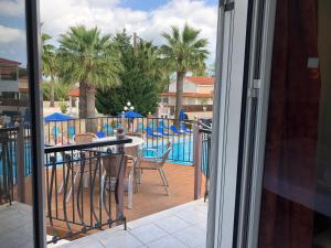 balcón con mesa, sillas y piscina en Paradise Apartments en Laganas