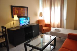 - un salon avec une télévision, un canapé et une table dans l'établissement Apartamentos Luxsevilla Palacio, à Séville