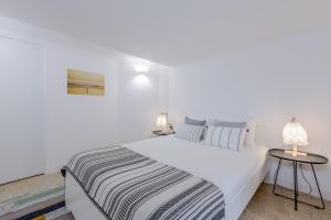 1 dormitorio blanco con 1 cama grande y 2 mesas en Renovated Typical Baixa Apartment, By TimeCooler, en Lisboa