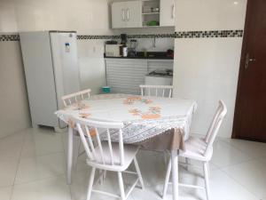 cocina con mesa, 2 sillas y nevera en Hospedagem Central II, en Arraial do Cabo