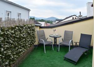a patio with chairs and a table on the grass at Apartmány Šitavanc in Příbor