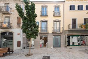 a tree in a courtyard in front of a building at Lovely and bright apartment in the heart of Banyoles in Banyoles