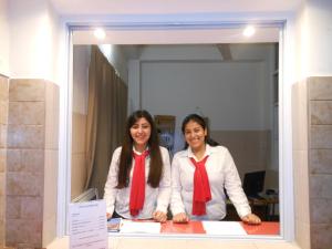 two women wearing red ties standing behind a window at Hotel Patricias 381 in San Salvador de Jujuy