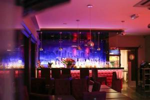 a bar in a restaurant with purple lighting at Hotel Skarpa in Sejny