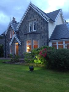 a large stone house with a window and a yard at Buccleuch Guest House in Fort William