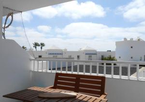 un balcón con un banco de madera sobre una barandilla blanca en Endless Blue Apartment, en Costa Teguise