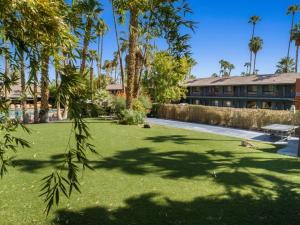 un edificio con un patio con palmeras y césped en Caliente Tropics en Palm Springs