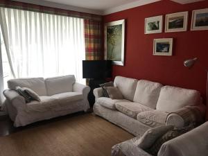 uma sala de estar com dois sofás brancos e uma parede vermelha em albobide em Bakio