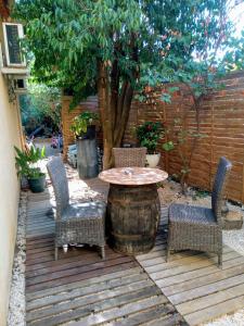 une terrasse en bois avec une table, des chaises et un arbre dans l'établissement Gite chez mamiyo gallargues le montueux, à Gallargues-le-Montueux
