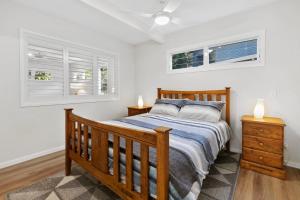 a bedroom with a wooden bed and two windows at Day Dreaming in Point Lookout
