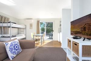 a living room with a couch and a tv and a bedroom at Huskisson Holiday Motel Cabins in Huskisson