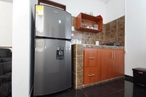 a kitchen with a stainless steel refrigerator and wooden cabinets at cozy apartment excellent location, air conditioning in Cali