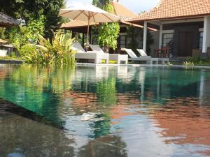 una piscina con sillas y sombrilla en The Amrita - Salt Farm Villas, en Tejakula