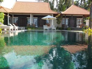 a swimming pool in front of a house at The Amrita - Salt Farm Villas in Tejakula