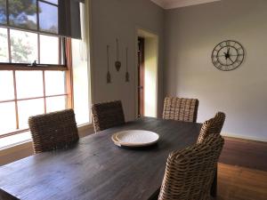 a dining room table with chairs and a clock on the wall at The Old Coolstore - Jonathon Apartment in Merricks North