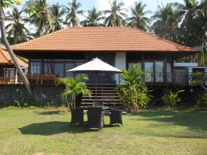 a house with an umbrella and chairs in front of it at The Amrita - Salt Farm Villas in Tejakula