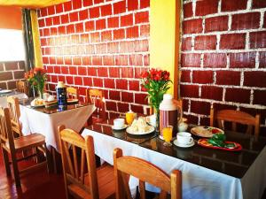 uma sala de jantar com uma mesa e uma parede de tijolos em Inka Khawarina Tambo Lodge em Ollantaytambo
